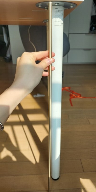 놋담 롱스틱을 이케아 책상 다리의 길이와 비교하는 사진. 책상 다리와 롱스틱의 길이가 거의 유사하다.