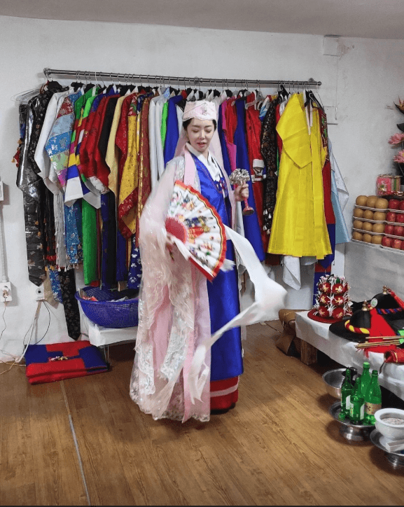 비단아씨가 점집에서 굿 의상일 입고 서 있는 모습