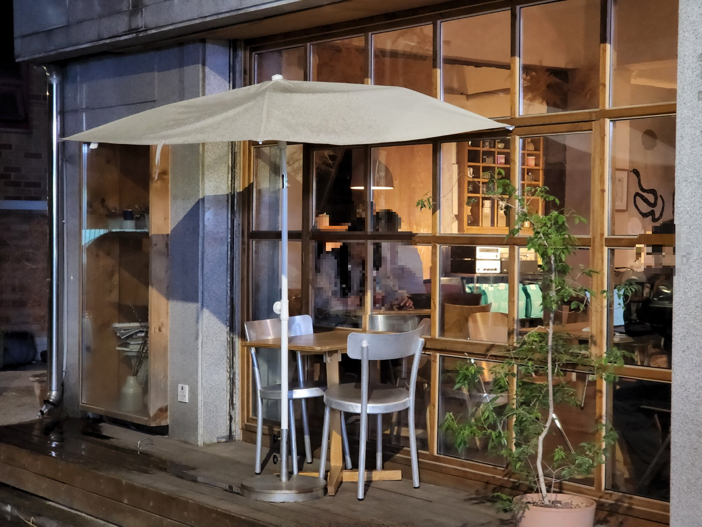 어둑해진 저녁에 카페 외부에서 바라보는 카페 야외 자리&amp;#44; 의자 2개와 함께 놓여있는 파라솔 자리
