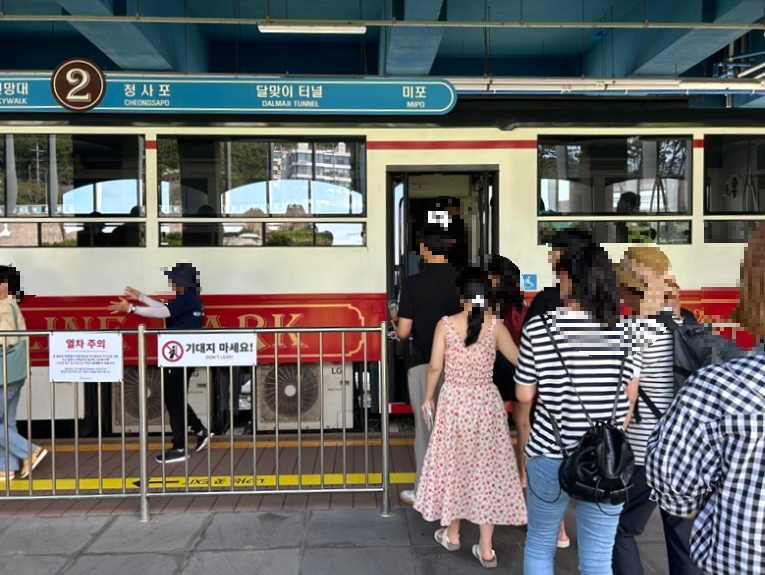 플랫폼에-정차한-빨간색과-하얀색이-섞인-열차-앞에-서있는-사람들을-찍은-사진