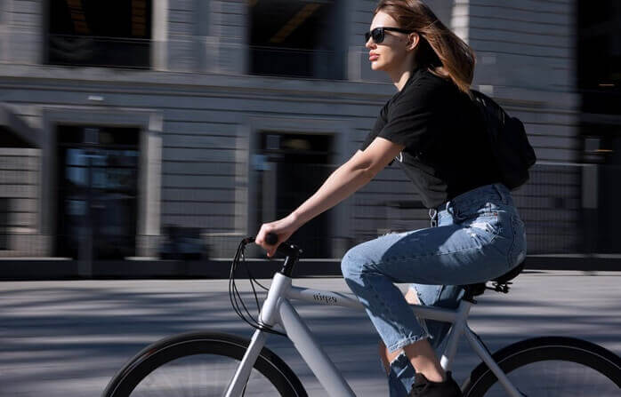 선글라스를 쓴 여자가 자전거를 타고 가고 있는 모습