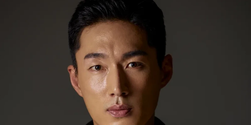 짙은 회색을 배경으로 머리를 올린 채 무표정으로 얼굴을 확대한 배우 김을호의 프로필 사진
