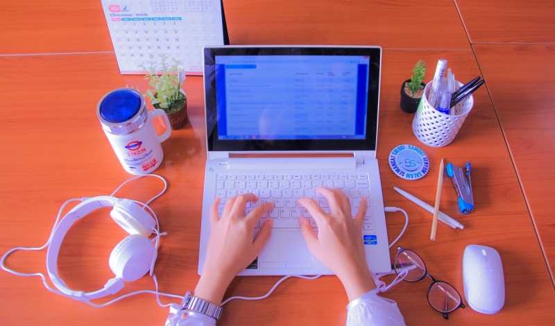 A content creator entering tax data on a laptop while organizing business expenses in a home office