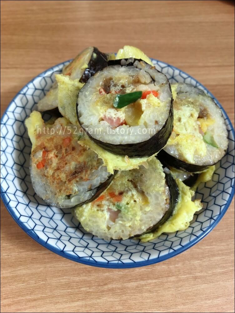 김밥에 계란옷을 입혀 만든 요리가가 둥근 접시에 담겨있다.