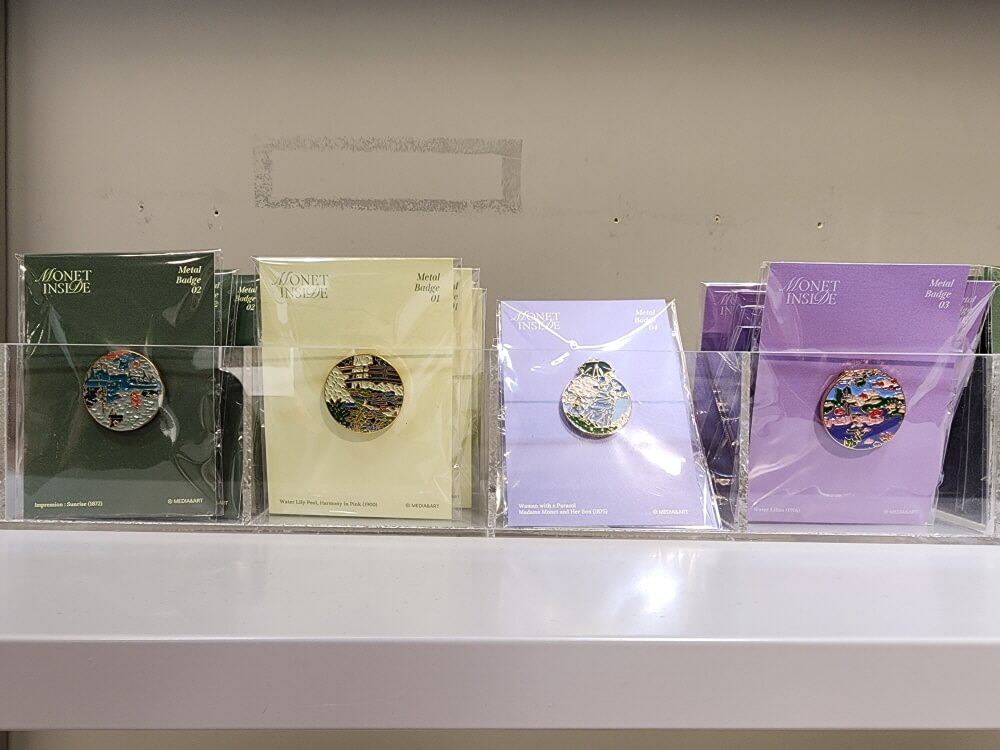모네 인사이드 굳즈 뱃지. 동그랗고 금속으로 만들어져 있고 안에 모네의 대표작이 그려져 있다.