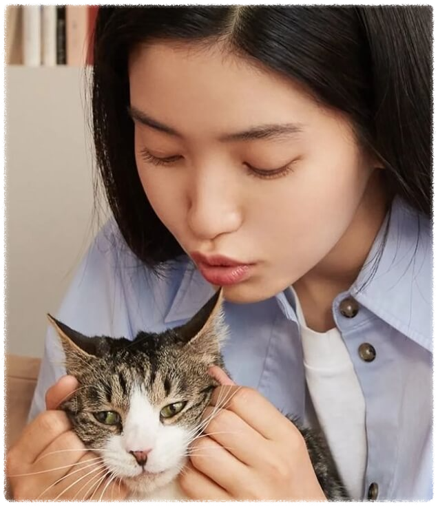 배우 김태리가 고양이 얼굴을 두 손으로 만지고 있는 장면.
