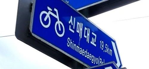 크로즈업 된 이정표&#44; 화살표 모양&#44; 진한 푸른 바탕에 흰 글씨&#44; 신매대교까지 19.5km&#44;