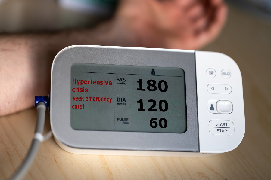 고혈압 환자가 팔에 전자혈압계를 대고 혈압을 재고 있는데&#44; 180-120&#44; 즉 고혈압임을 나타내고 있는 혈압계를 찍은 사진