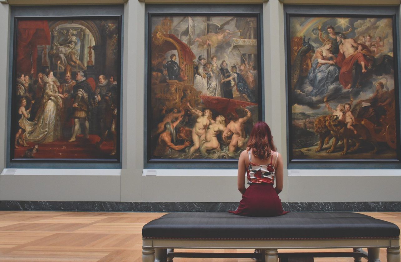 한 여성이 미술관 벤치에 앉아 미술품을 감상하고 있다