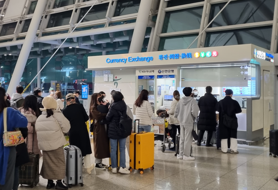 인천공항 환전창구에 사람들이 줄을 서있다.