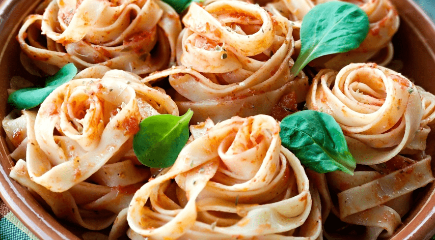 A bowl of pasta and pasta are displayed like flowers. The pasta bowl is pretty and well decorated.