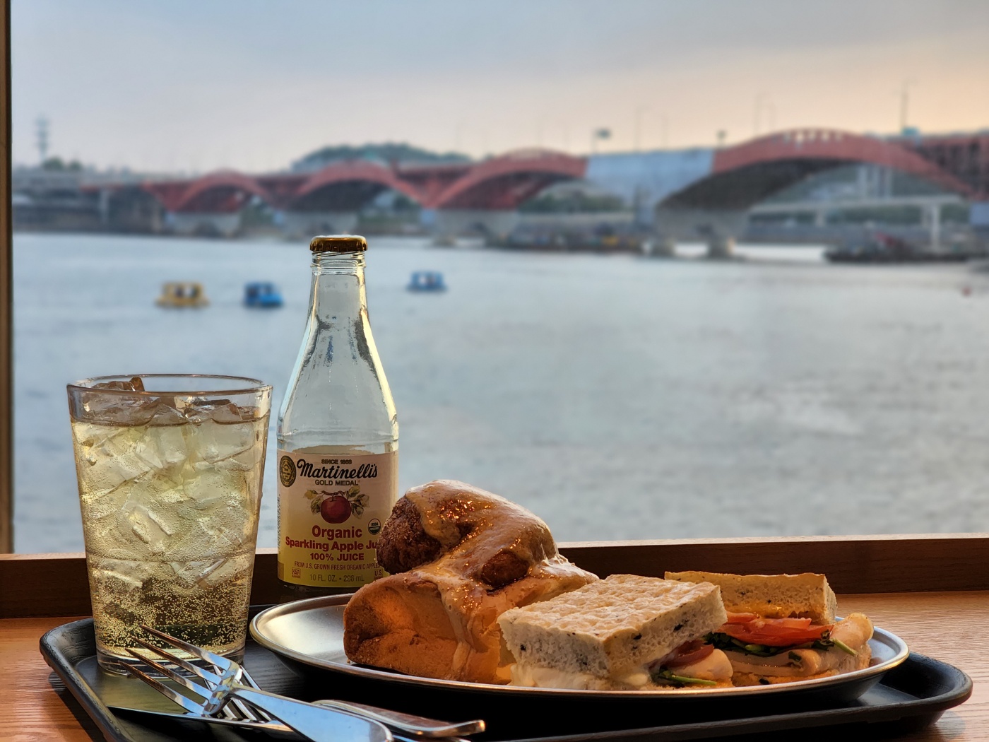 성산대교&#44; 전동보트&#44; 한강이 보이는 유리창 1인 바 테이블에 올려 있는 병음료와 샌드위치&#44; 시나몬롤 스타벅스 메뉴