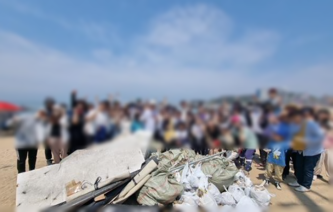 해양 쓰레기를 줍고 다같이 모여서 사진찍는 사람들