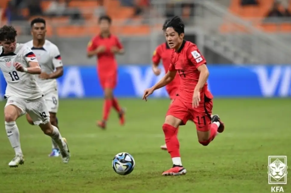 축구장 붉은 국가대표 유니폼을 입고 공을 드리블하고 있는 양민혁