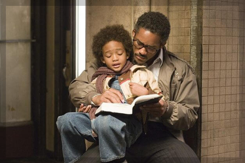 아빠가 아들을 무릎위에 앉혀 놓고 함께 책을 보고있다.