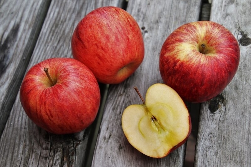 빨간 사과 3개와 쪼개진 사과 하나가 있는 사진