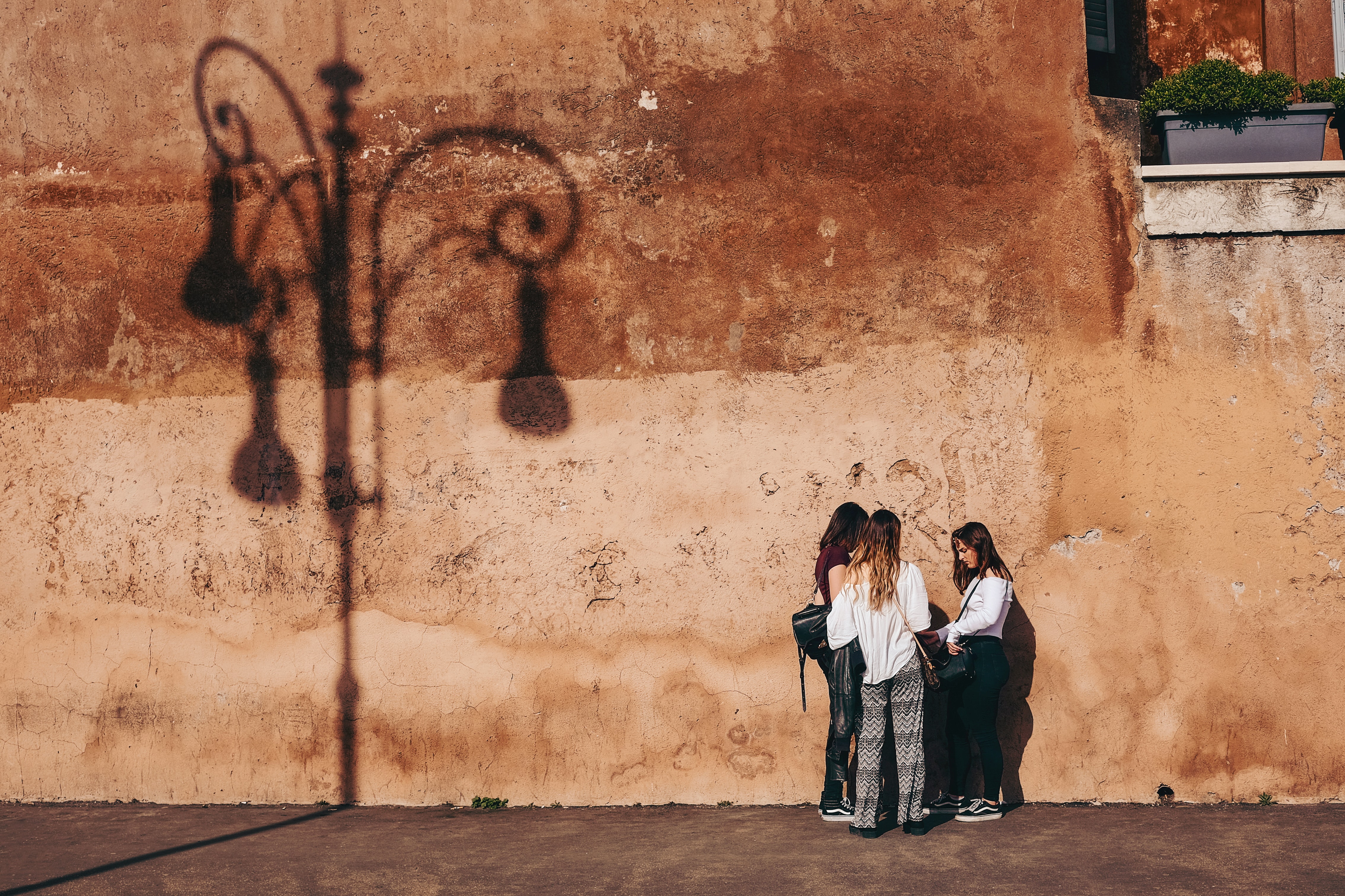 이탈리아 로마의 한 벽에 서서 의논하고 있는 세 명의 여성 모습