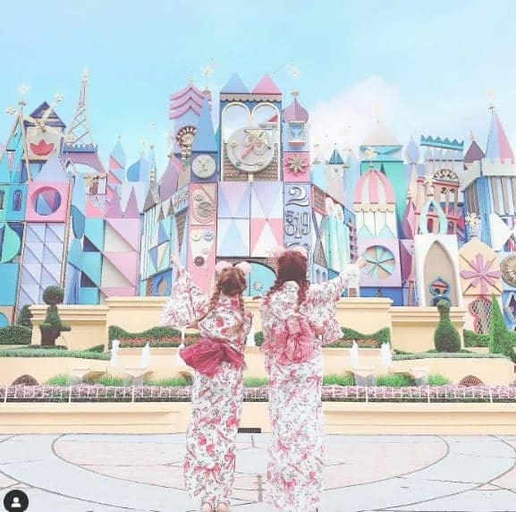파스텔 색감의 장난감 조각상 성 앞에서 여성 두명이 서 있는 뒷 모습