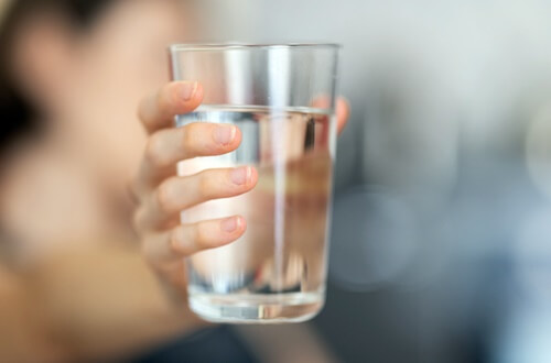 물이 들어있는 투명한 유리컵을 내밀고 있는 손