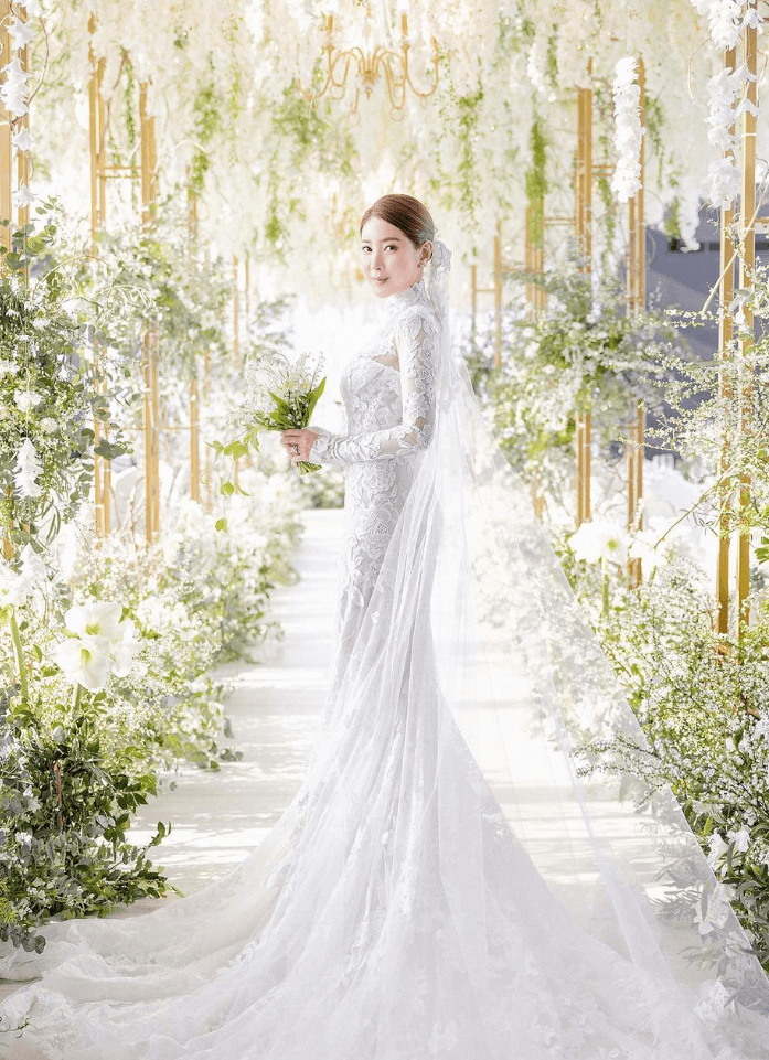서인영이 1억원 상당의 꽃 장식을 한 결혼예식장에서 하얀색 결혼 드레스를 입고 부케를 들고 비스듬히 서있다.