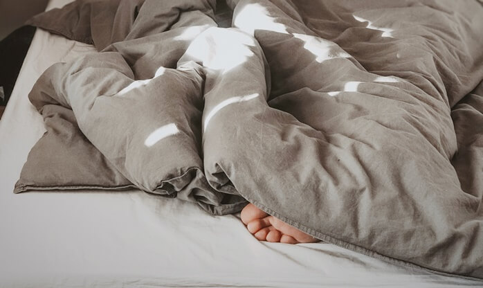 침대 위 이불 밖으로 나와있는 잠자는 사람의 발가락