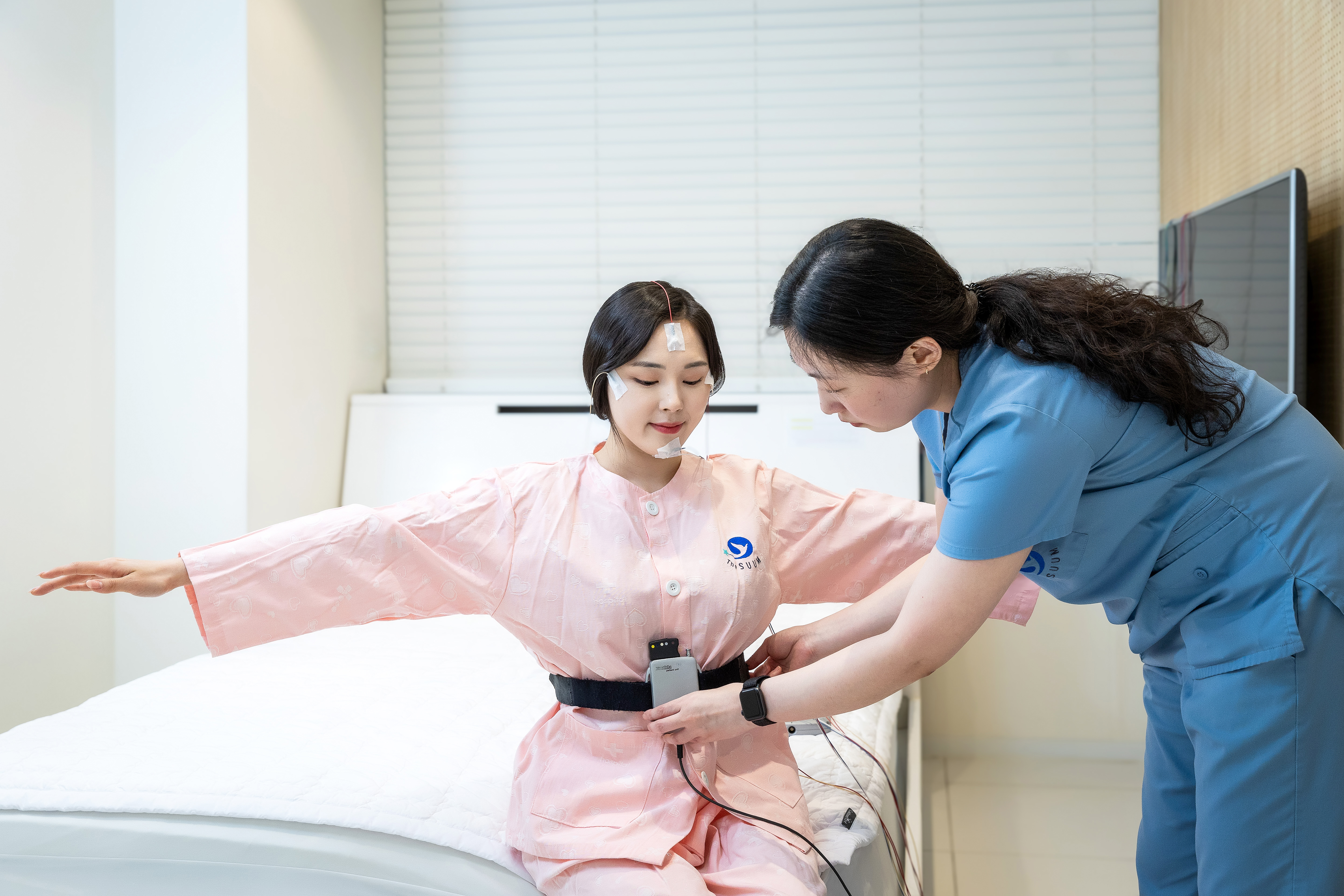 젊은 여성이 숨수면클리닉 의료진의 도움을 받아 수면다원검사 준비를 하고 있다.