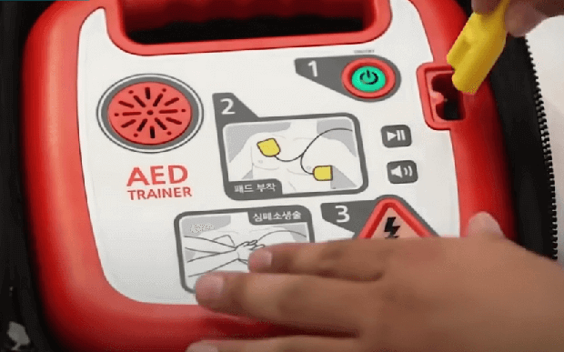 심장-충격기-AED-모습-전면에는-사용-순서가-그려져-있고-전원-버튼과-안내-지시가-나오는-스피커가-있다