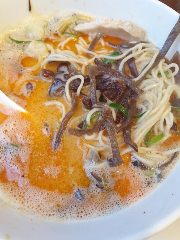 카라 빠이탄 라멘을 휘저은 모습. 갈색 해조류 같은 고명이 많이 보이고 양념이 섞여 국물이 더 빨개졌다.