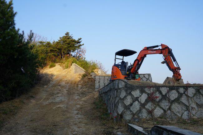 푸른 하늘&#44; 묘원 작업중인 오렌지색 포크레인&#44; 왼쪽엔 동산&#44;