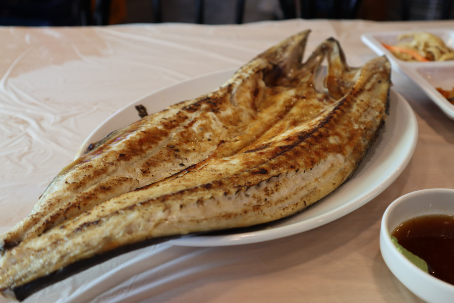 바다에서 채취를 한 고등어를 반으로 갈라서 노릿노릿하게 잘 구워서 흰색 접시에 담아서 식탁 위에 올려놓고 찍은 사진