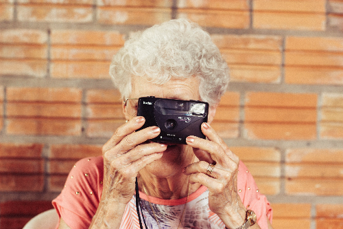 머리가 하얀 할머니가 카메라로 사진을 찍는 모습