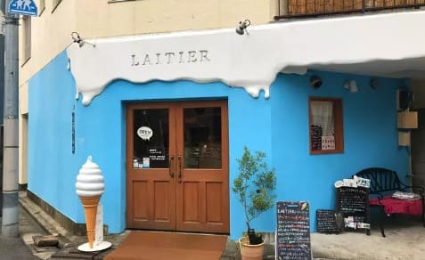 아이스크림 콘 모양의 모형이 파란색 가게 앞에 놓여져 있다.