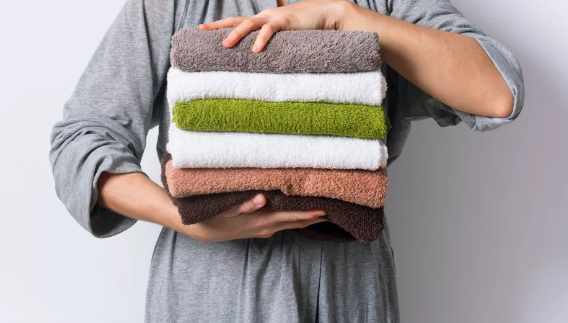 수건 세탁법-수건 더미를 들고 있는 여성(이미지 출처: Shutterstock)
