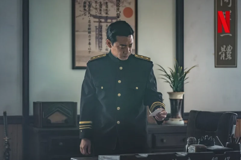 일본 경찰복을 입고 서 있는 이시카와 역을 맡은 배우 김도현