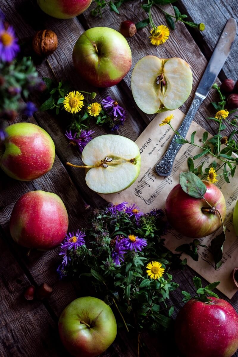 칼과 사과와 작은 꽃들이 나무 식탁위에 있는 사진