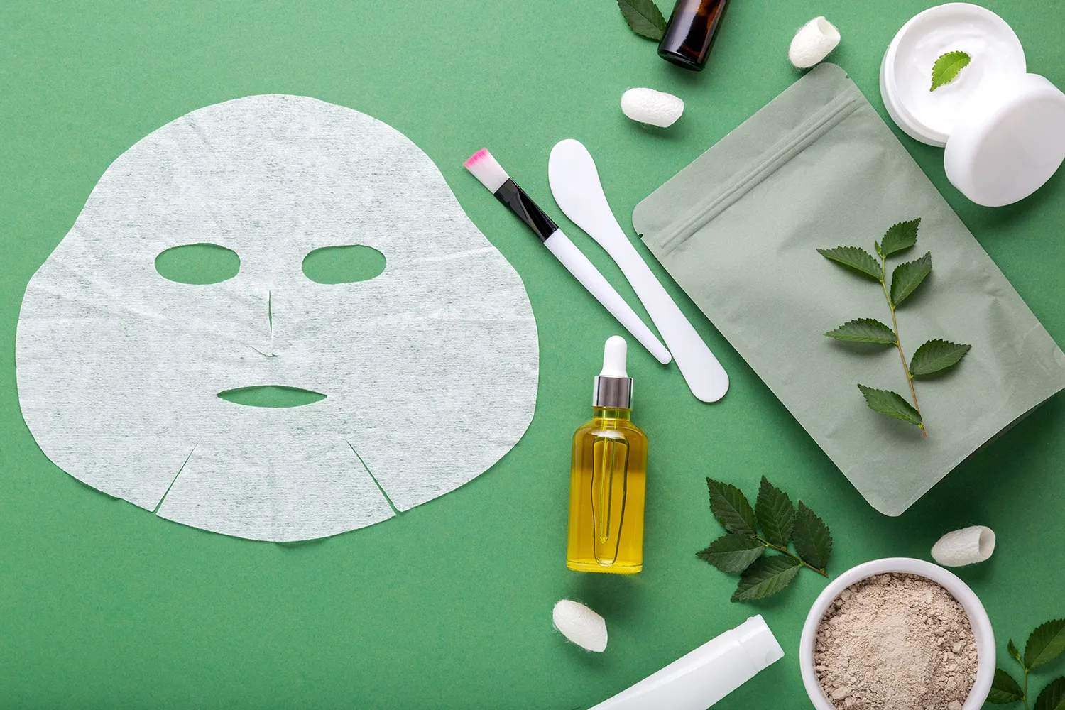 나뭇잎이있는 녹색 배경에 화장품과 얼굴 마스크