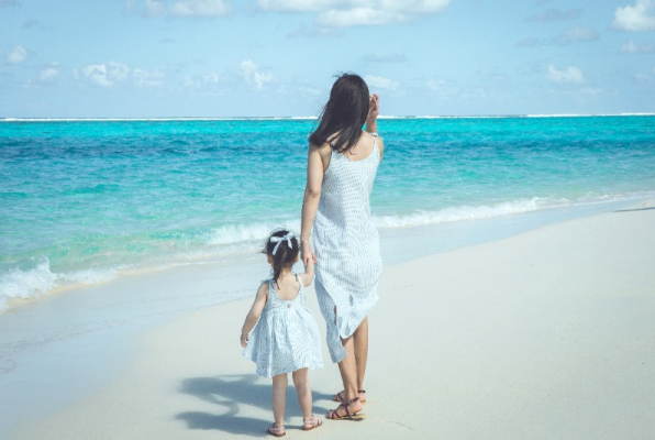 바닷가에서 엄마와 딸이 손을 잡고 있는 모습.