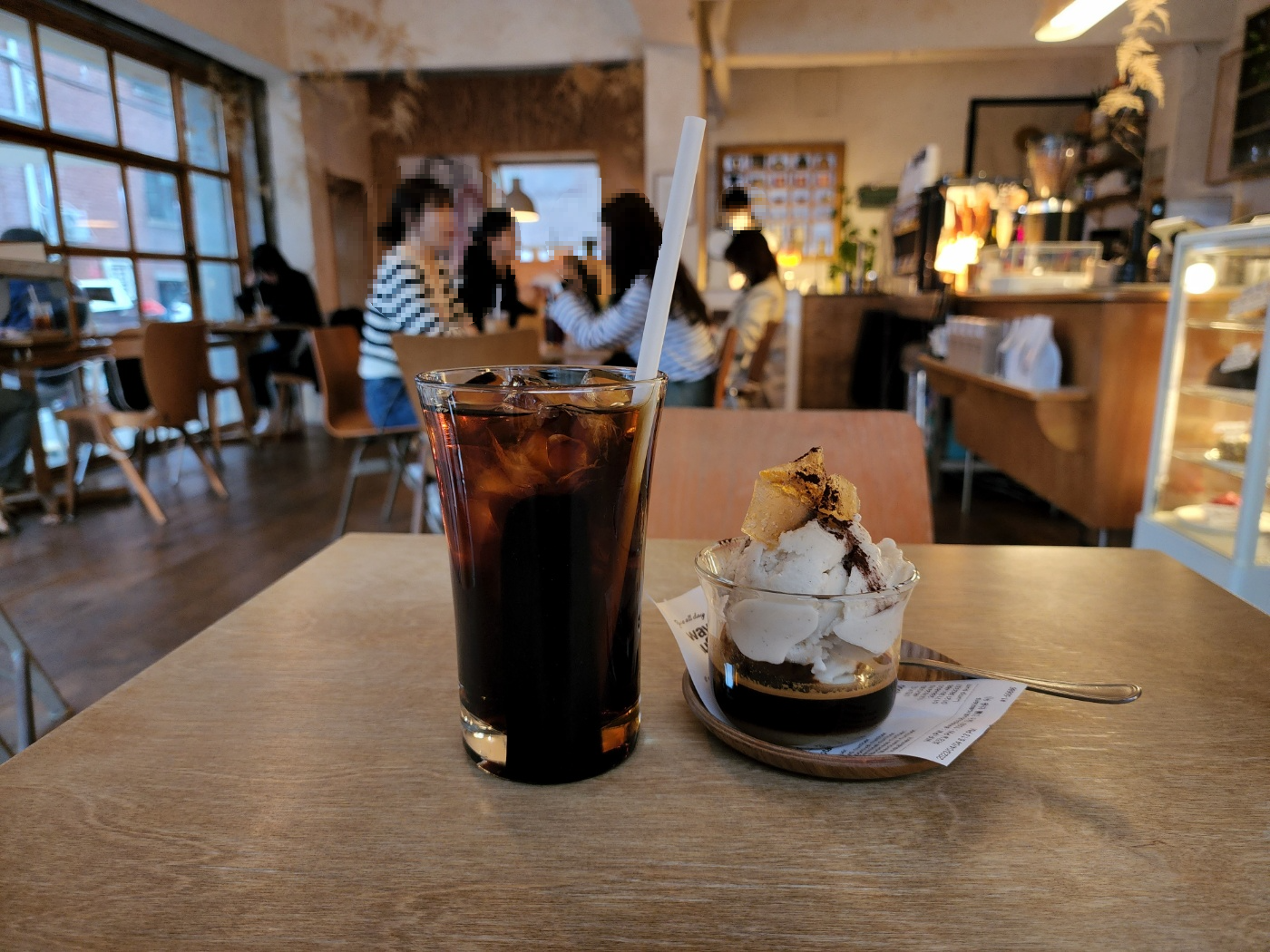 카페 내부 좌석을 배경으로 한 빨대가 있는 아이스 커피 한 잔과 아이스크림이 위에 올려진 에스프레소 한 컵