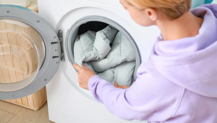 코트를 세탁기에 넣는 여성(이미지 출처: 셔터스톡)