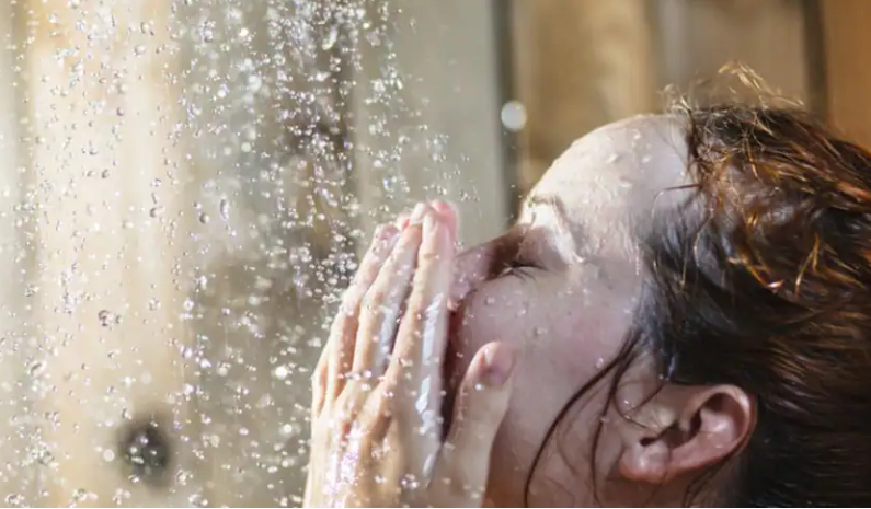 샤워를 하고 있는 여성의 얼굴 물방울들이 여성의 얼굴에 닿고 있는 사진