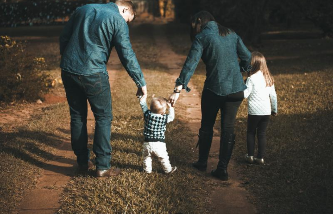 아기의 양손을 잡고 있는 가족의 모습