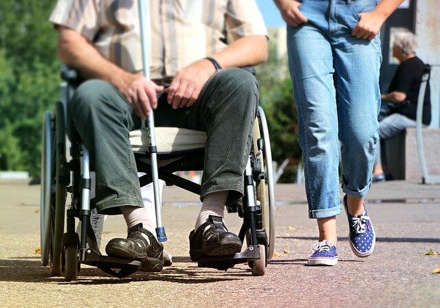 휠체어에 탄 환자와 함께 걸어가는 동행자