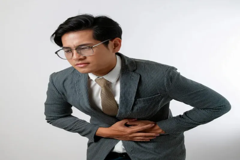 스트레스로 복부를 움켜쥐고 있는 남성의 건강 문제 표현 사진입니다.