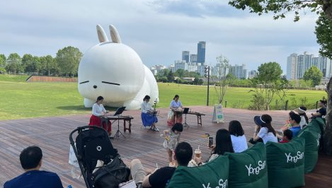 한복을 입고 가야금을 연주하는 모습을 지켜보는 관객들