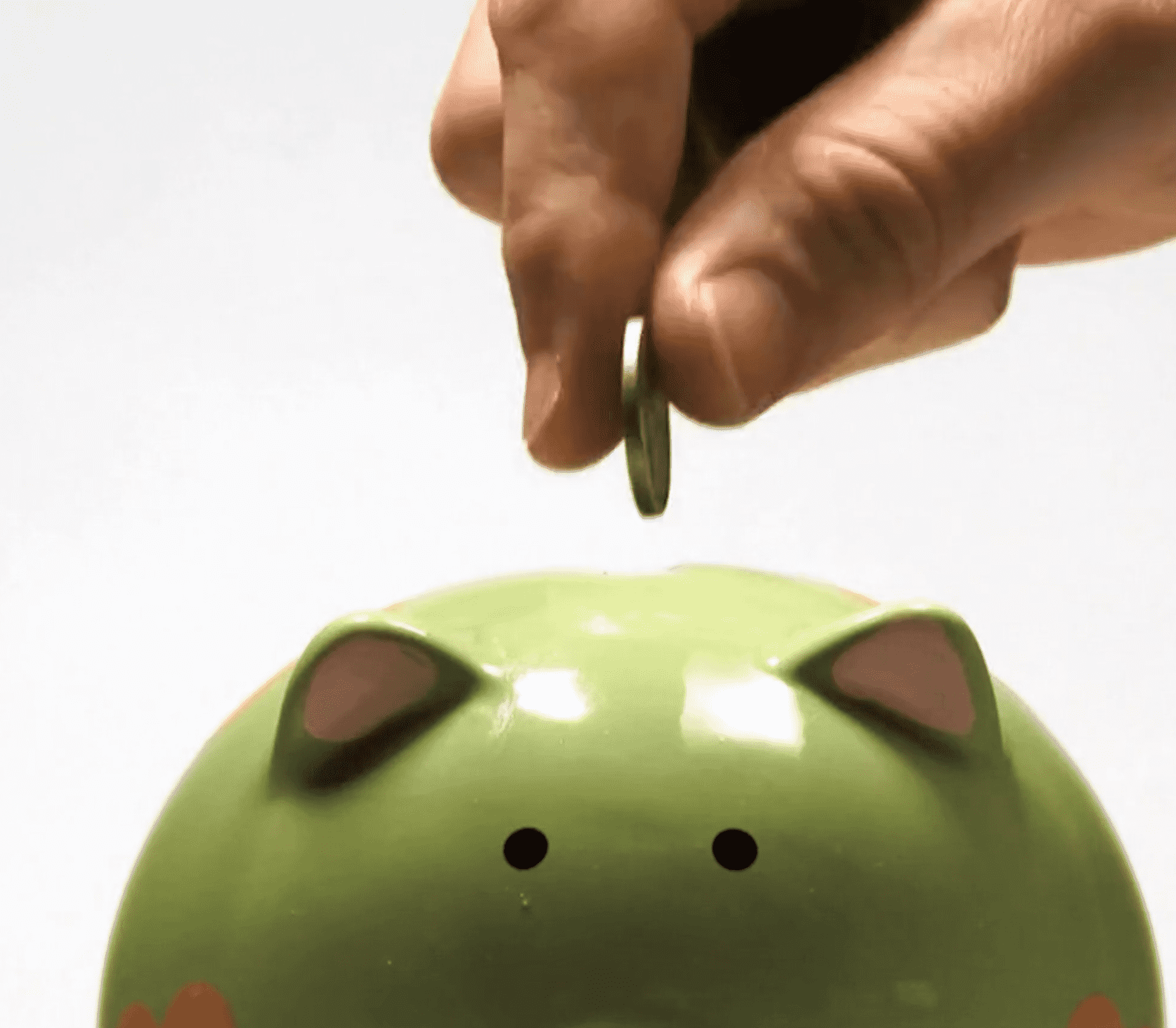 Someone is putting a coin into the piggy bank