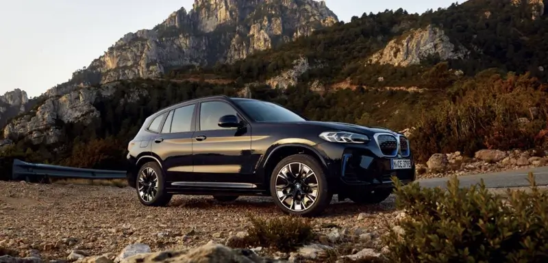 BMW-iX3-2023년형이-산악-도로에-주차되어-있는-옆-모습