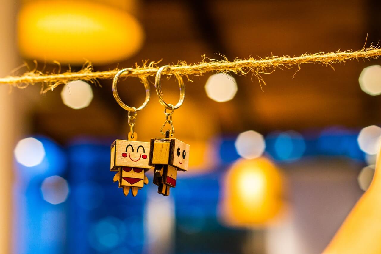 나무로 만든 로봇이 달려있는 2개의 열쇠고리가 끈에 달려있는 사진