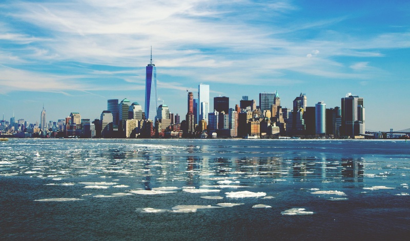 Panoramic view of Manhattan skyline from across the Hudson River with floating ice – representing U.S. immigration, urban life, and residency freedom