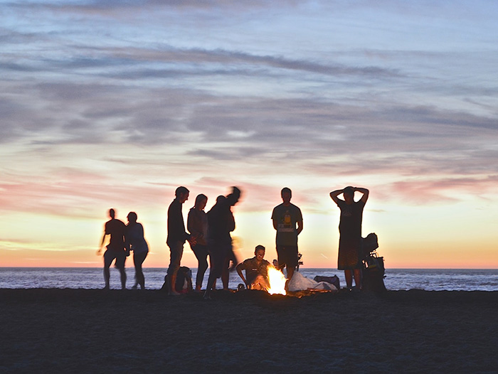 저녁 해변에 한 무리의 사람들이 모여 불을 피우고 얘기를 나누고 있다