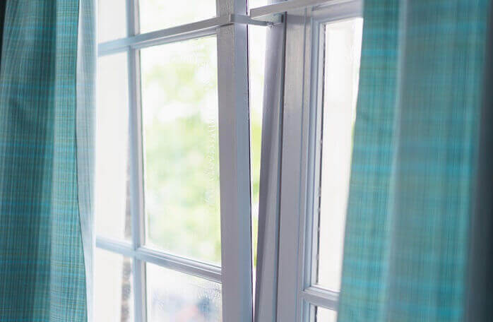 청록색의 커튼이 달려 있는 하얀 색상 창틀의 창문